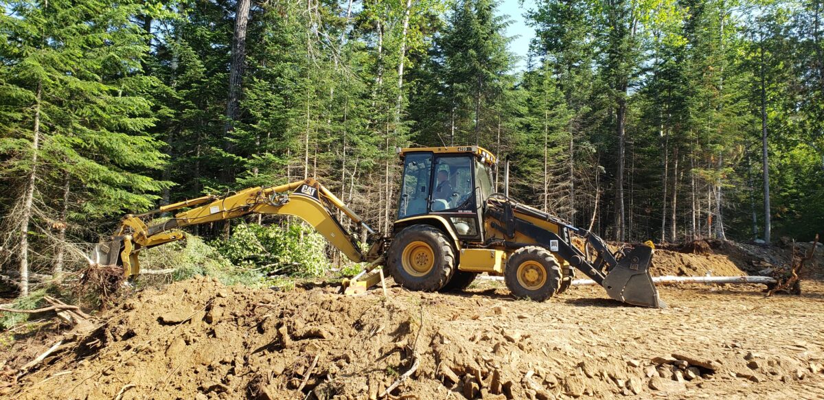 backhoe with thumb clearing trees